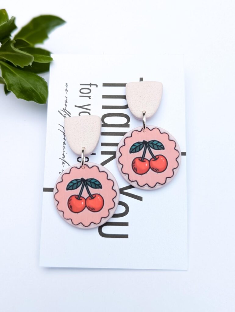 Handmade pink cherry dangle earrings with a scalloped edge.
