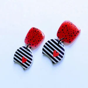 Two black and white striped earrings featuring small red heart charms hanging from them.