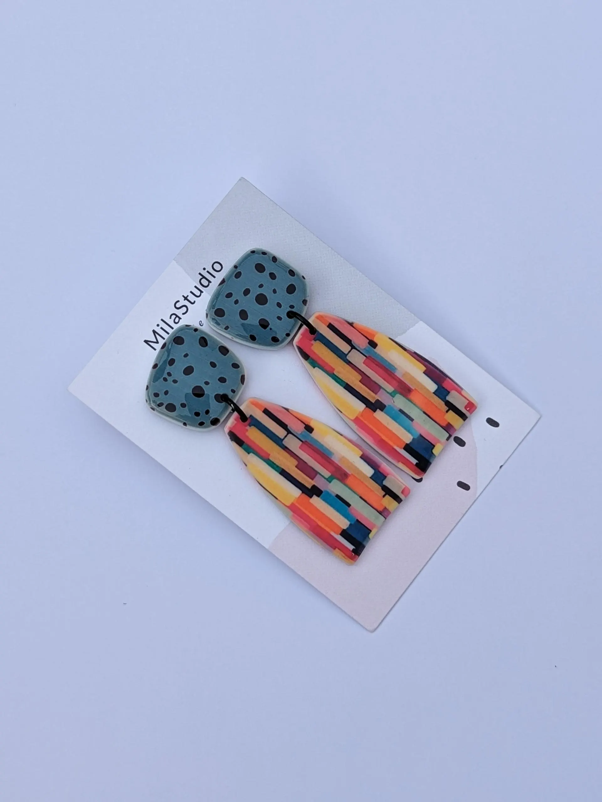 Colourful dangle earrings with a blue top and a patterned bottom.