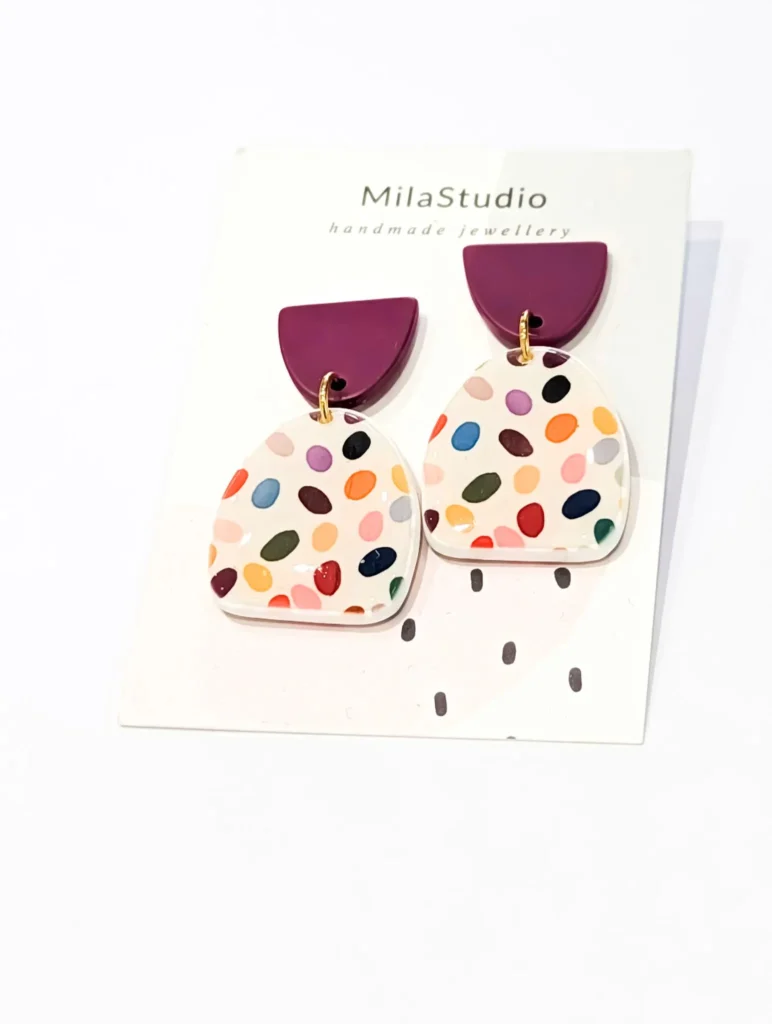Close-up of handmade round checkered earrings showing the vibrant colours and detailed pattern.