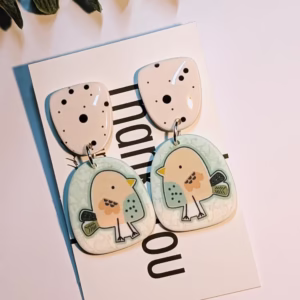 Bird earrings on a background with a plastic green plant