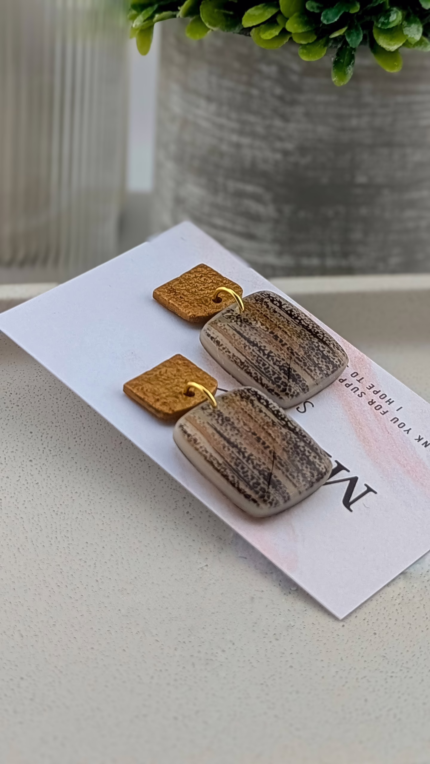 Earthy statement earrings in charcoal, sand, and ochre with a high-gloss resin finish and metallic gold clay tops.