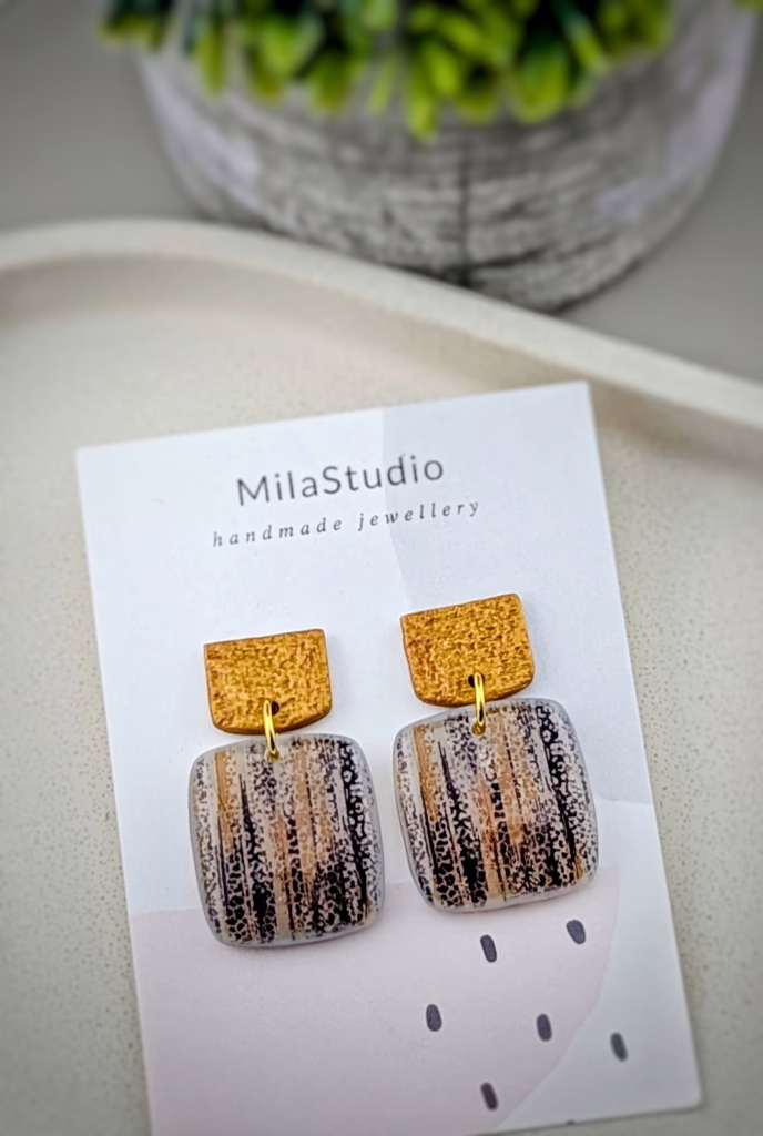 Handcrafted polymer clay dangle earrings featuring a vertical white birch bark texture and metallic gold-coloured hammered studs.