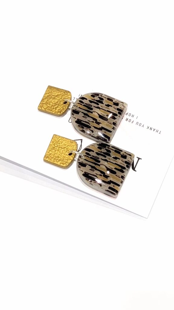 Pair of handmade Art Deco statement earrings with an abstract ochre and black patterned dangle and square gold-coloured hammered studs.