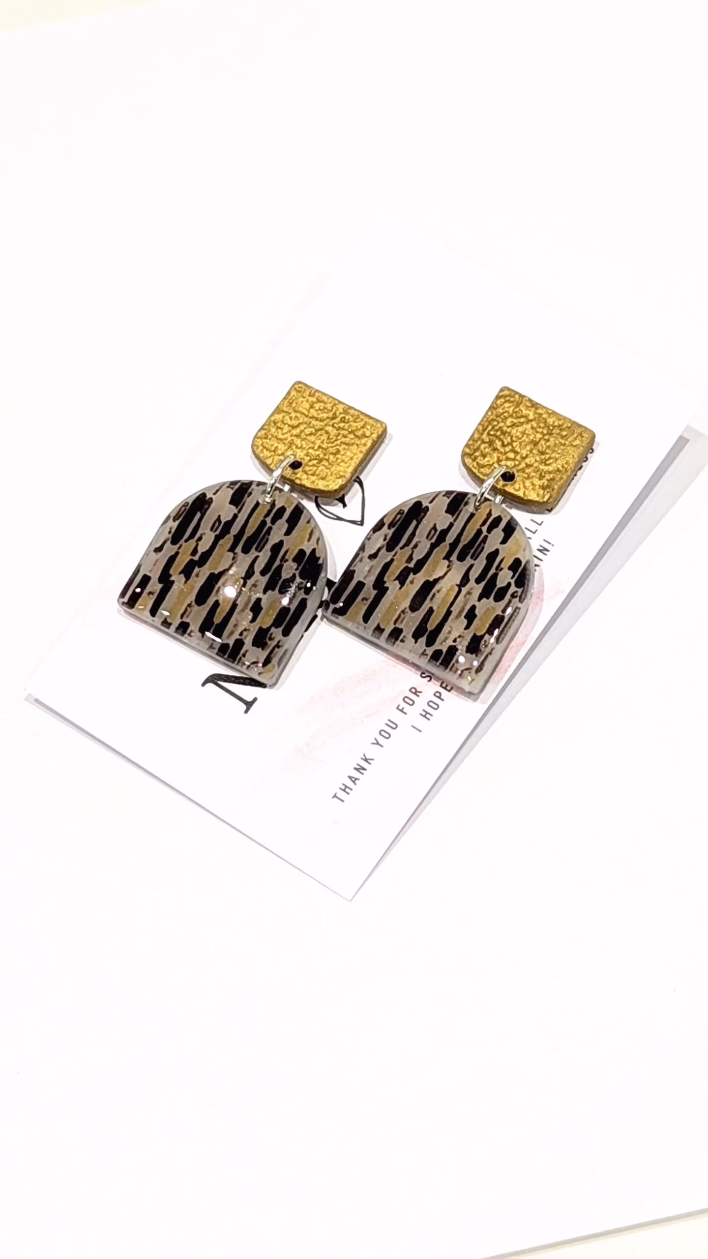 Close-up of square metallic gold-effect polymer clay studs featuring a hand-applied hammered texture.